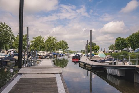 Scenic Stays on the Water Welcome to your peaceful riverside escape in Maurik, where floor-to-ceiling windows frame uninterrupted views of the Lower Rhine and harbor. This stylish holiday home offers an inviting open-plan layout filled with natural l...